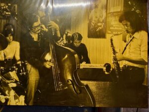 picture of Jiro Akamatsu (far light) playing saxophone in his younger days at jazz spot 'Blue Note'